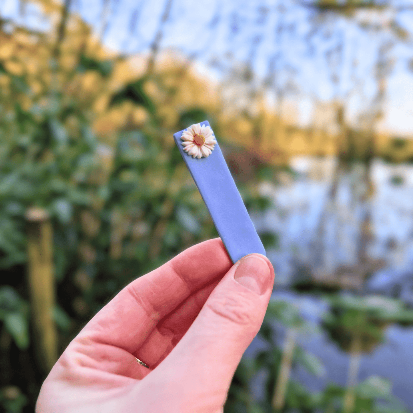 Daisy Decorative Blue Plant Tag with Hand for Scale Thumbnail.