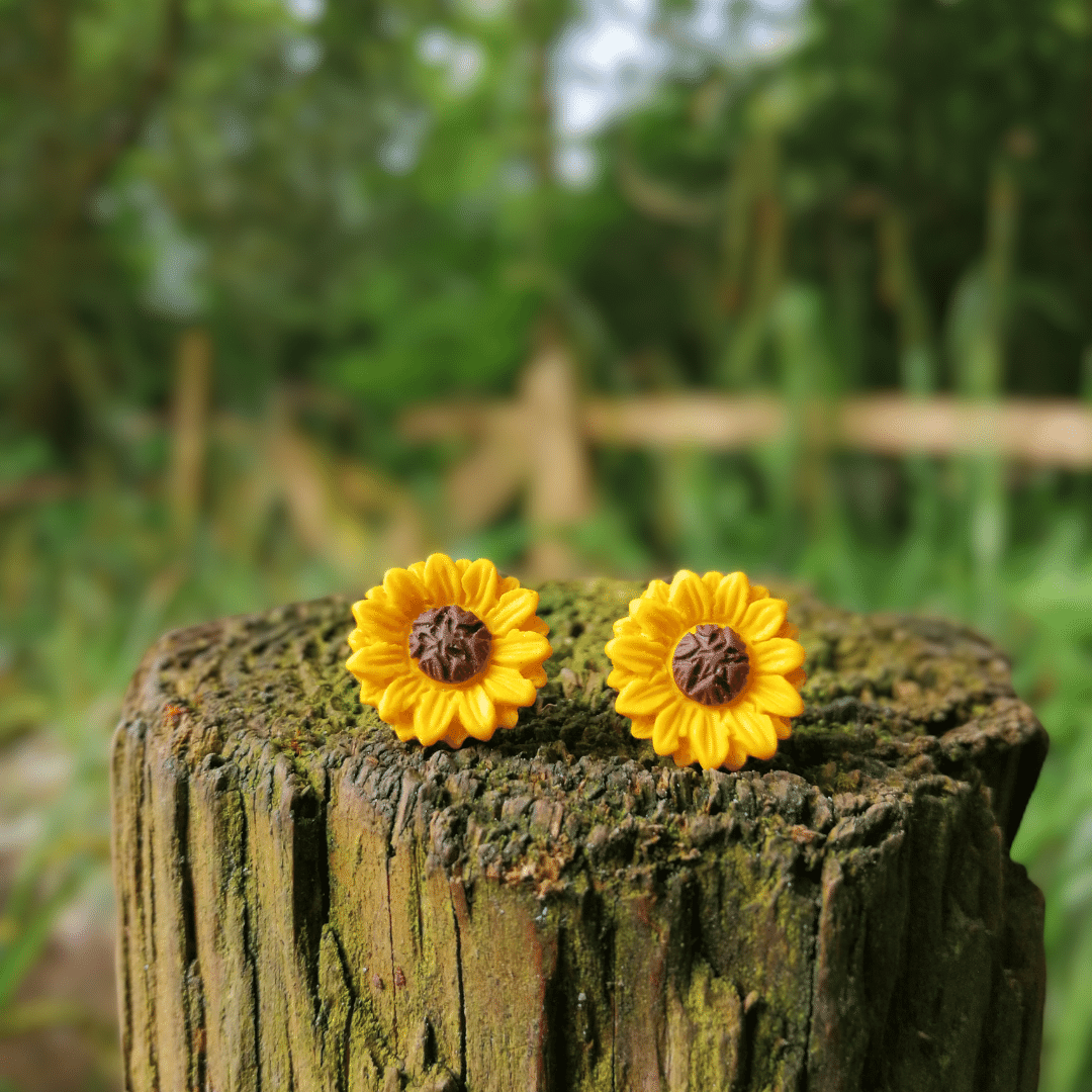 Front view of polymer clay joyful Sunflower studs on wooden post.