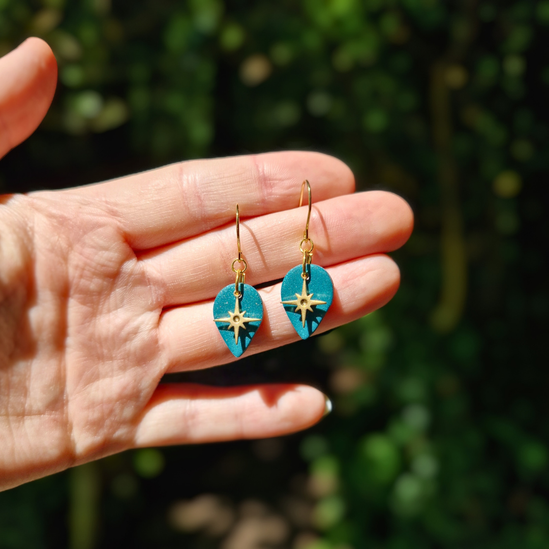 Hand for Scale Image of the Glitter Green North Star Teardrop Earrings with Nature Background