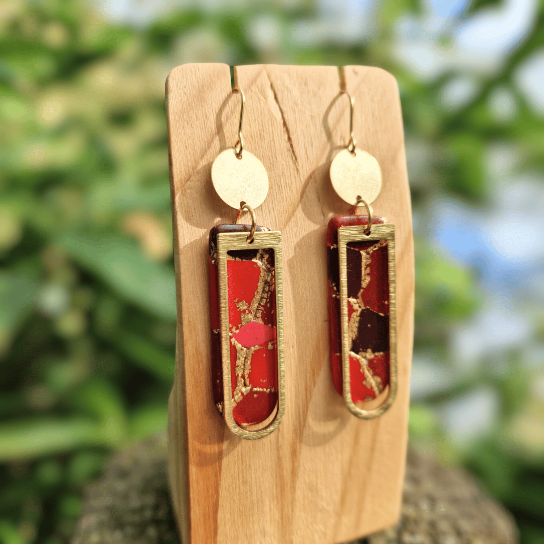Close up Image of our Reds and Gold Long Arch Earrings with Raw Brass Charms.