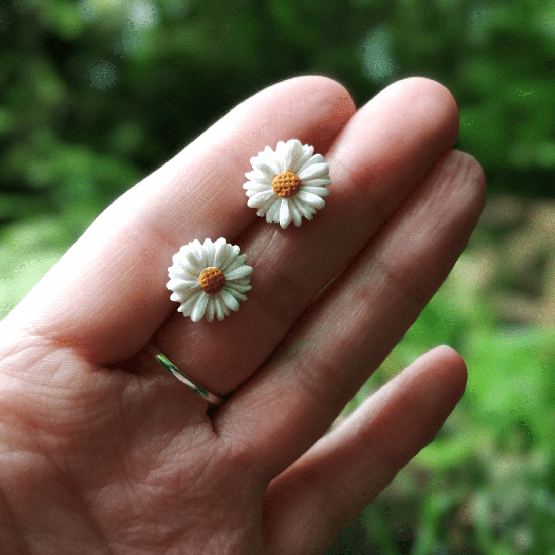 Minimalist Daisy Stud Earrings in Hand for Scale with Nature Background.