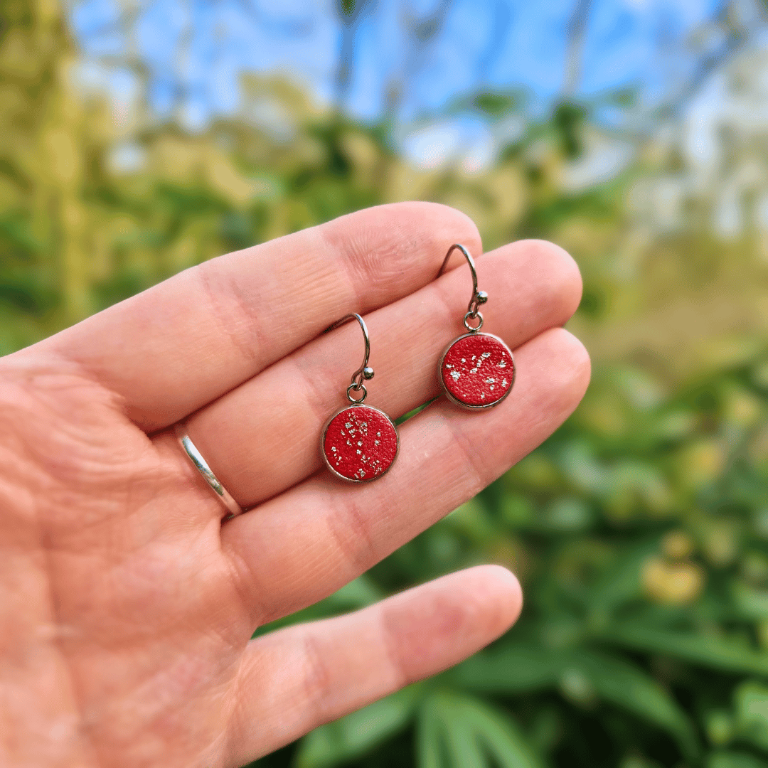 Hand for Scale Image of the Zero Waste Reds and Silver Polymer Clay Tray Earrings with Nature Background.