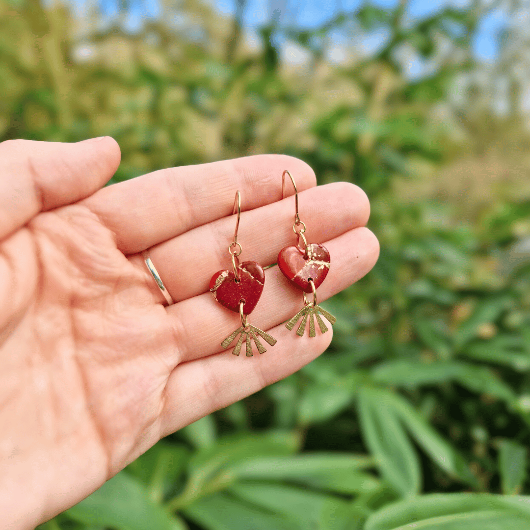 Hand for Scale Image of our Polymer Clay Zero Waste Heart and Fan Hooks with Nature Background.