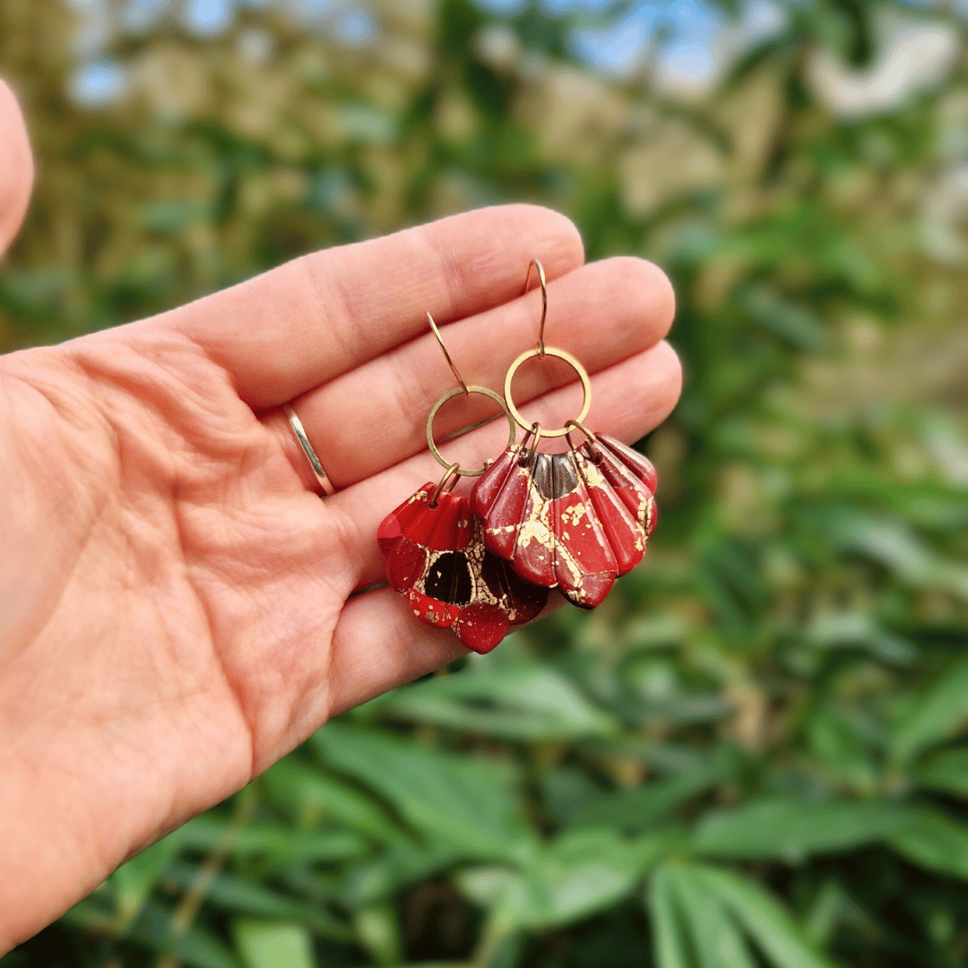 Hand for Scale Image for Option 1 of the Reds and Gold Zero Waste Shell Earrings with Nature Background.