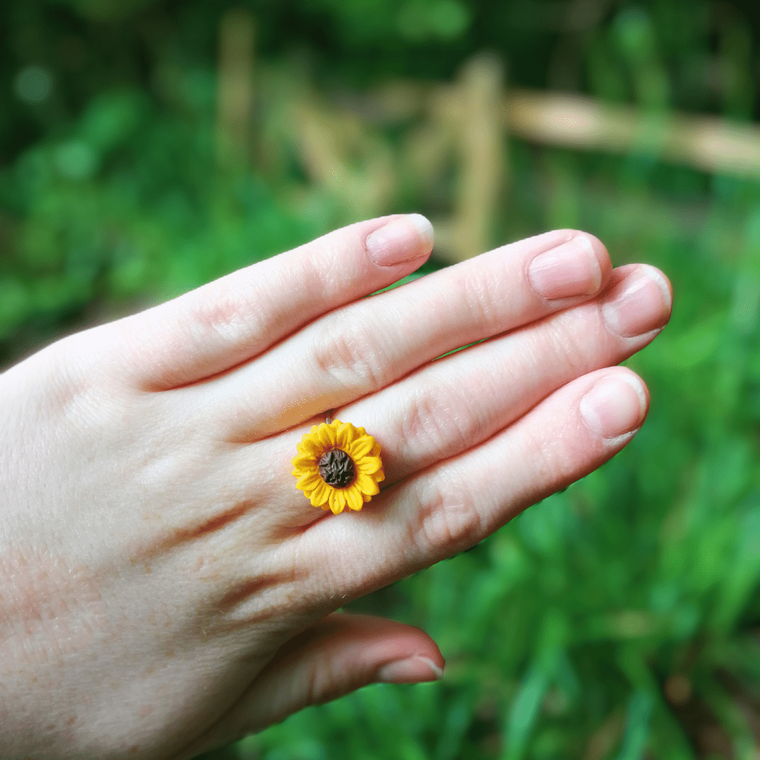 Wearing our adjustable intricate polymer clay sunflower ring with hand for scale.
