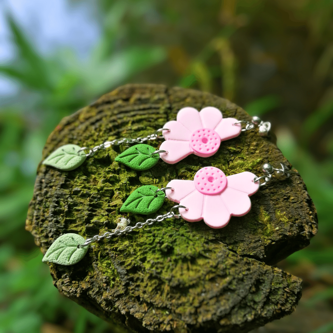 Pink Polymer Clay Mirrored Wild Daisy and Leaf Drop studs Displayed on Wooden Post in Nature.