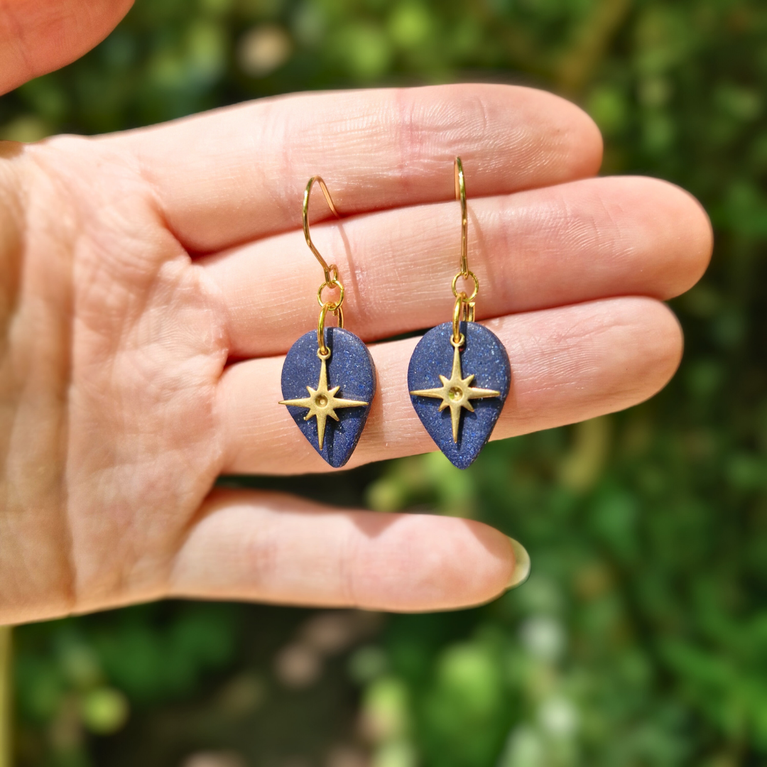 Hand for Scale Image of the Glitter Blue North Star Teardrop Earrings with Nature Background