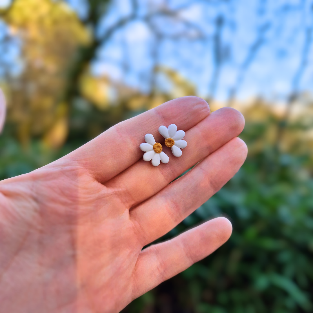 Mini Half Daisy Studs in Hand for Scale with Nature Background.